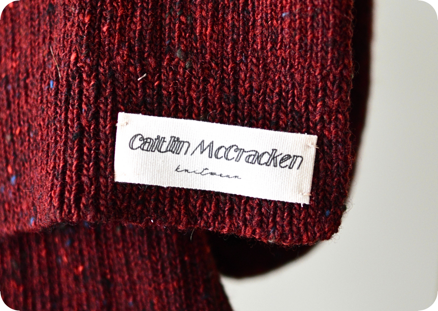 Close-up of a red knit scarf with a label on a white background
