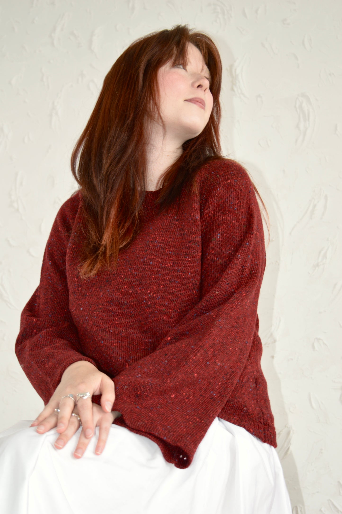 Low angle of the Bell Sweater in red, model sitting down