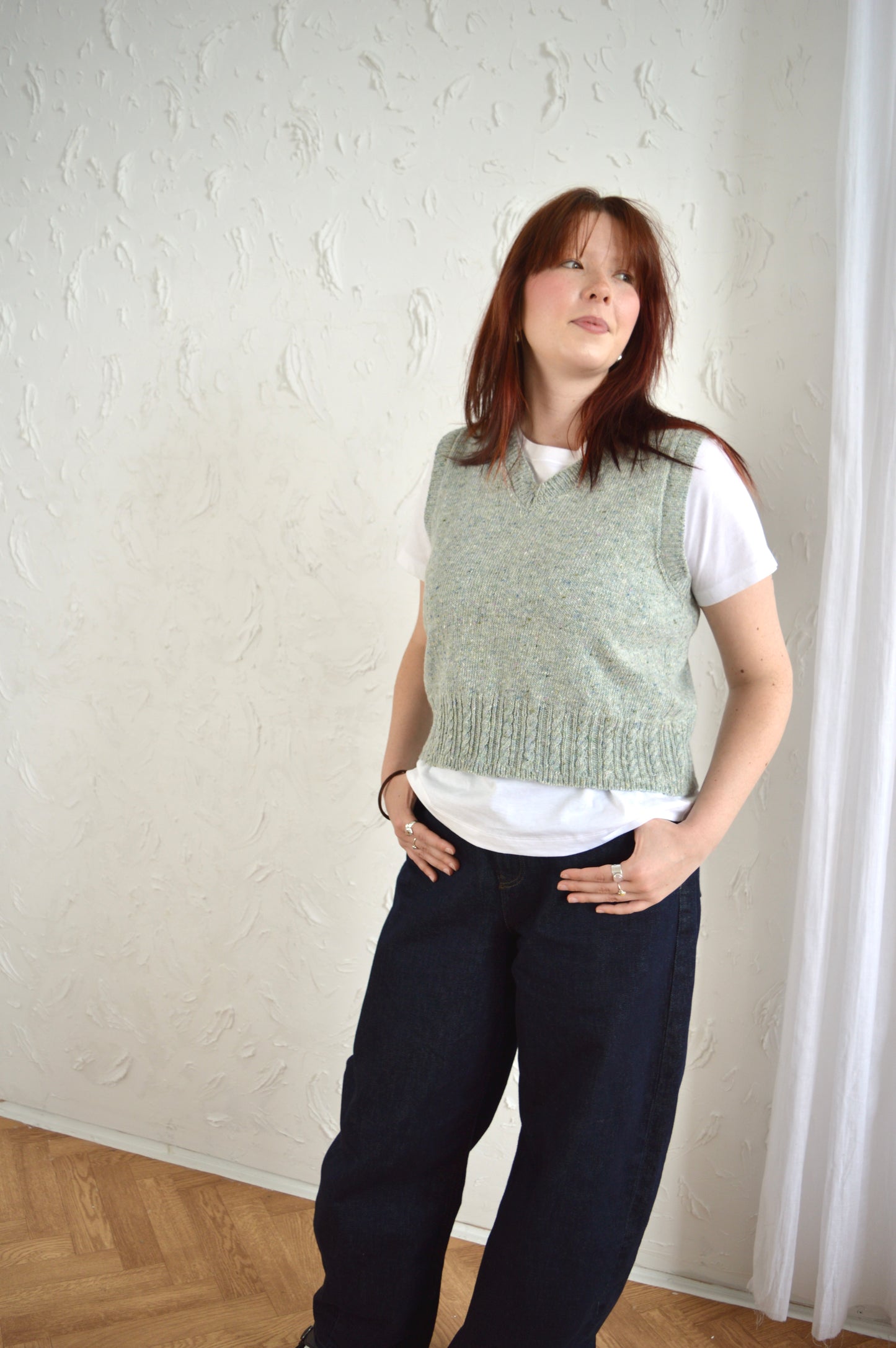 Model wears The Cable Vest in light grey, styled with white T-shirt and jeans