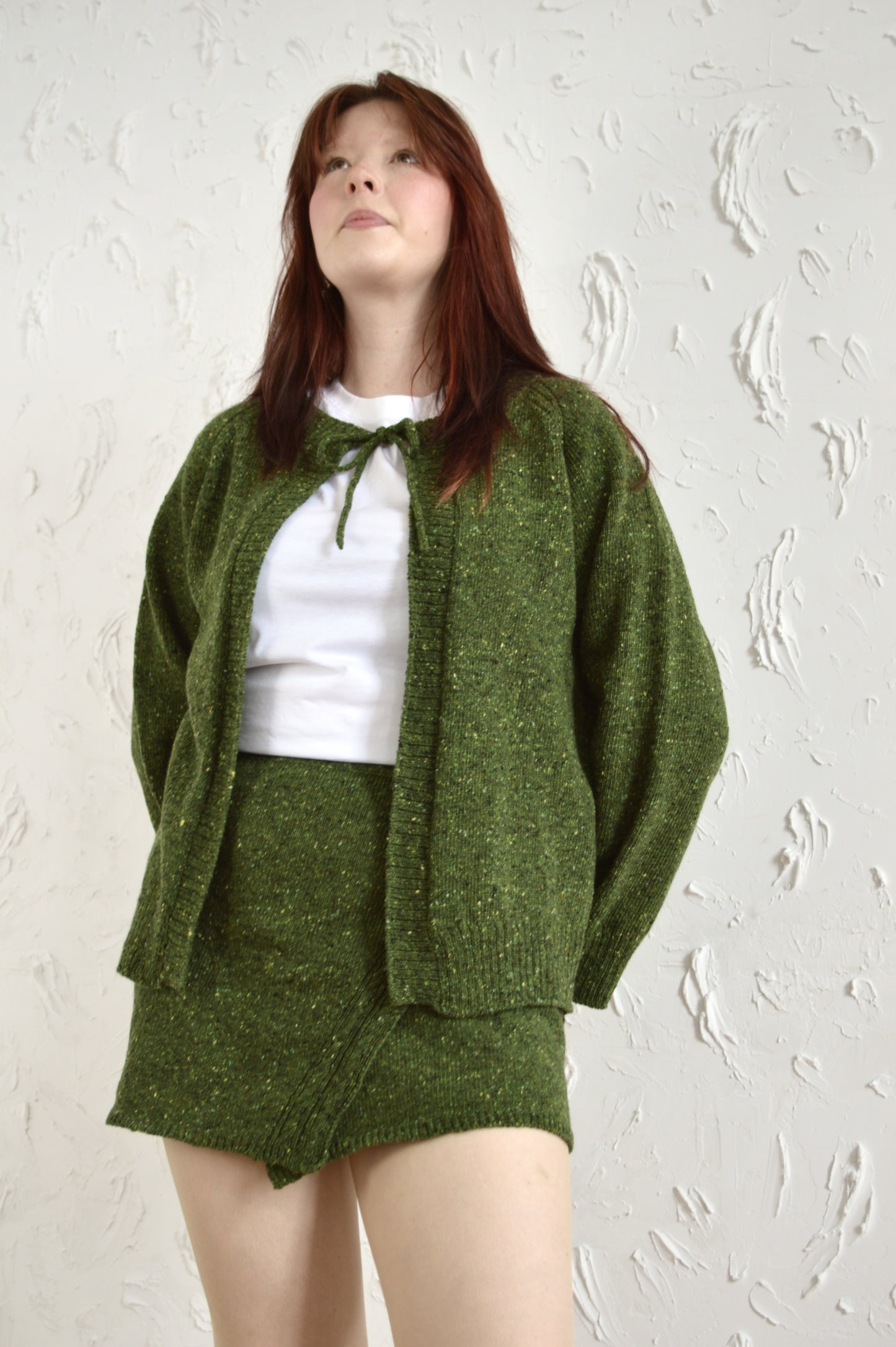 Model wearing The Cosy Cardi in green, paired with The Wrap Skirt