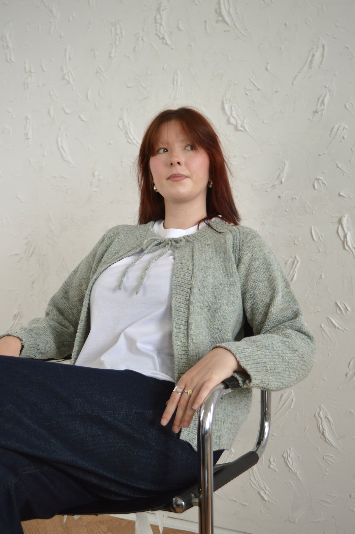 Model sitting wearing The Cosy Cardi in light grey