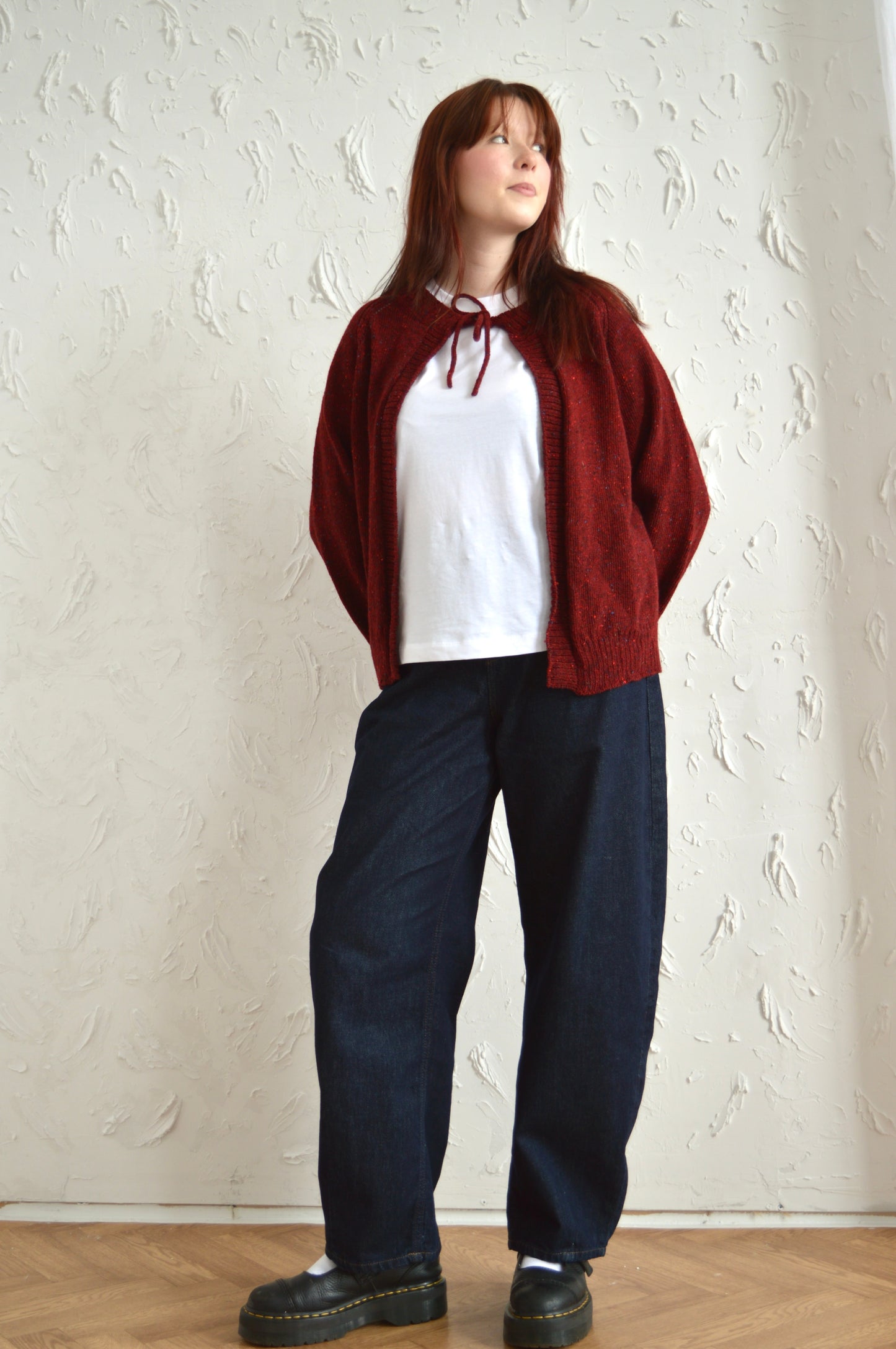 Full length view of model wearing The Cosy Cardi in red, styled with white tshirt, jeans and black shoes