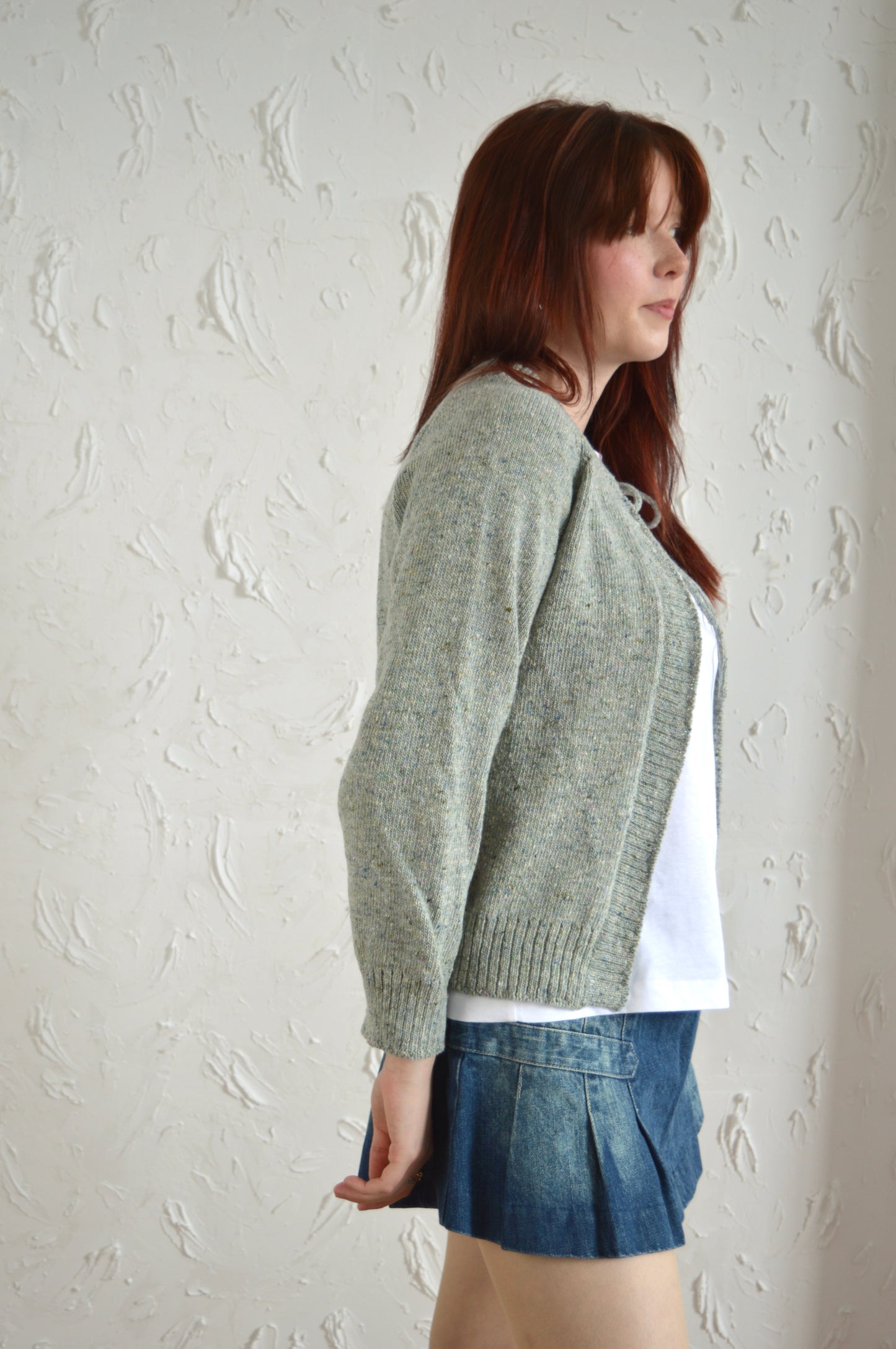 Side view of The Cosy cardi in light grey, styled with a denim mini skirt
