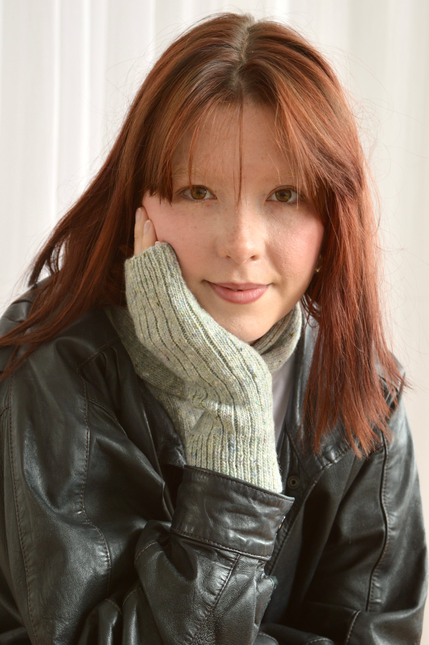 Model wears The Fingerless Gloves in light grey with hand rested on chin