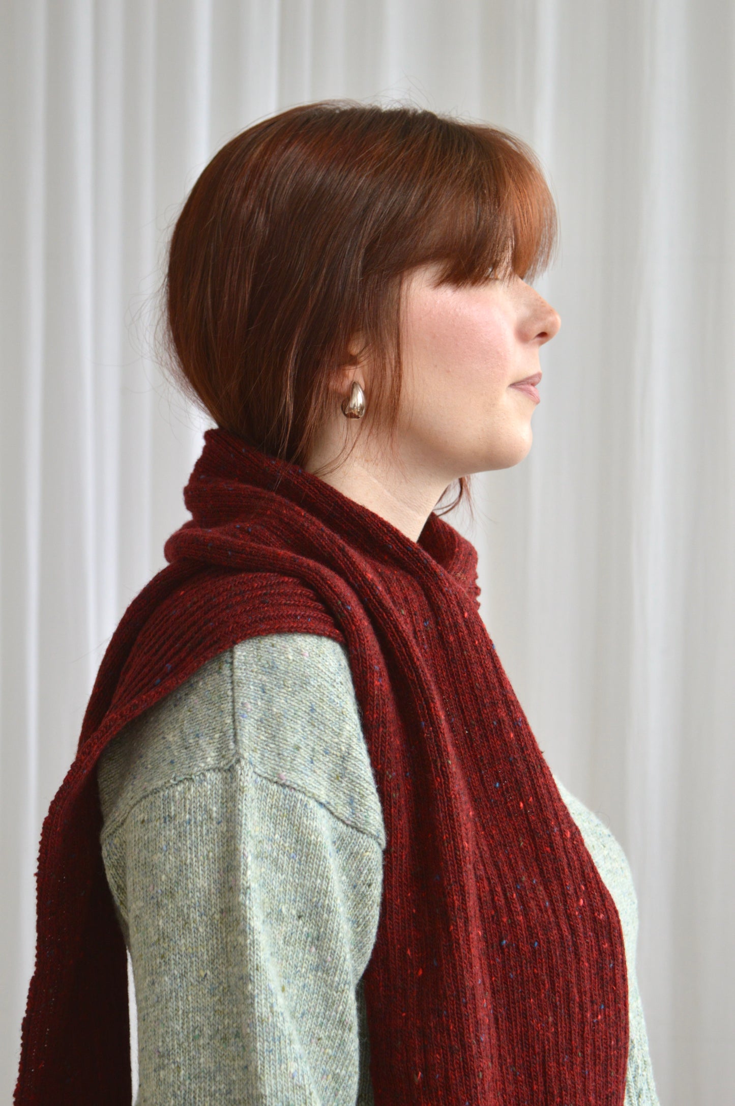 Side view of model wearing the reversible rib scarf in red