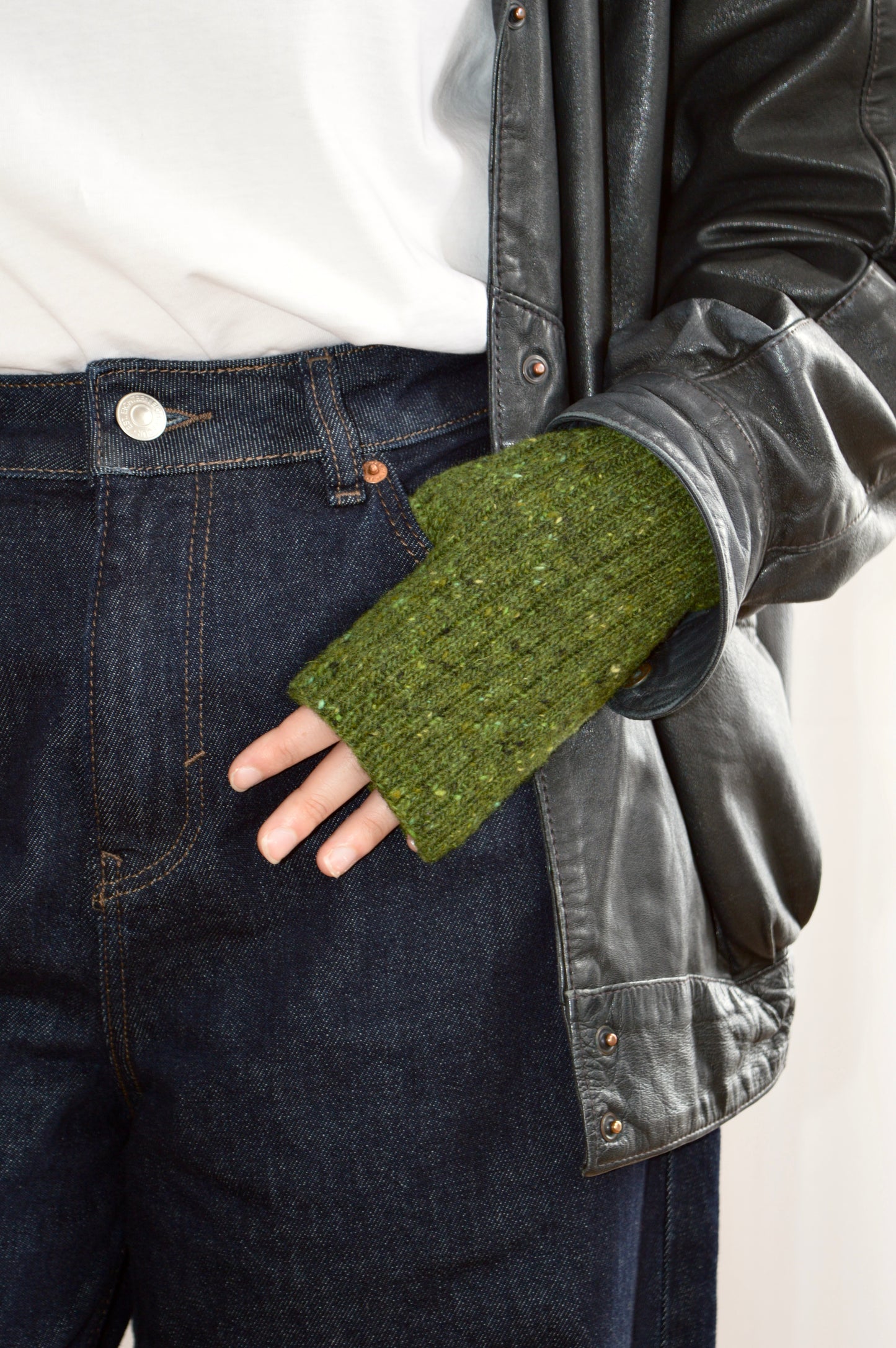 Model wears the fingerless glove in green with hand in pocket of jeans, styled with white T shirt and leather jacket