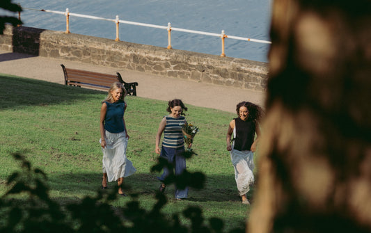 Three women running up a hill wearing Caitlin McCracken new knitwear collection