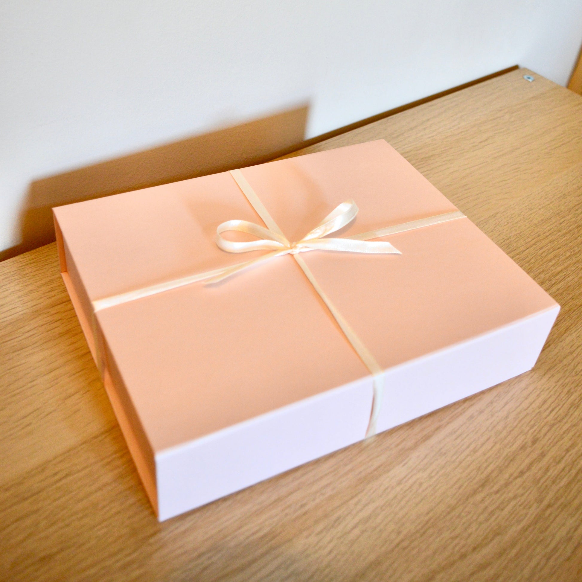 Gift box with a white ribbon on a wooden surface