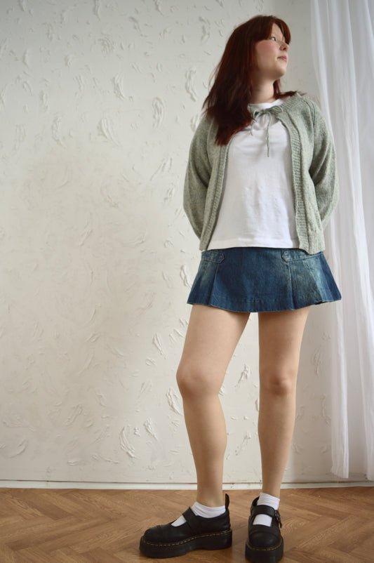 Full body shot of model wearing The Cosy cardi in light grey, styled with denim mini skirt and black shoes.