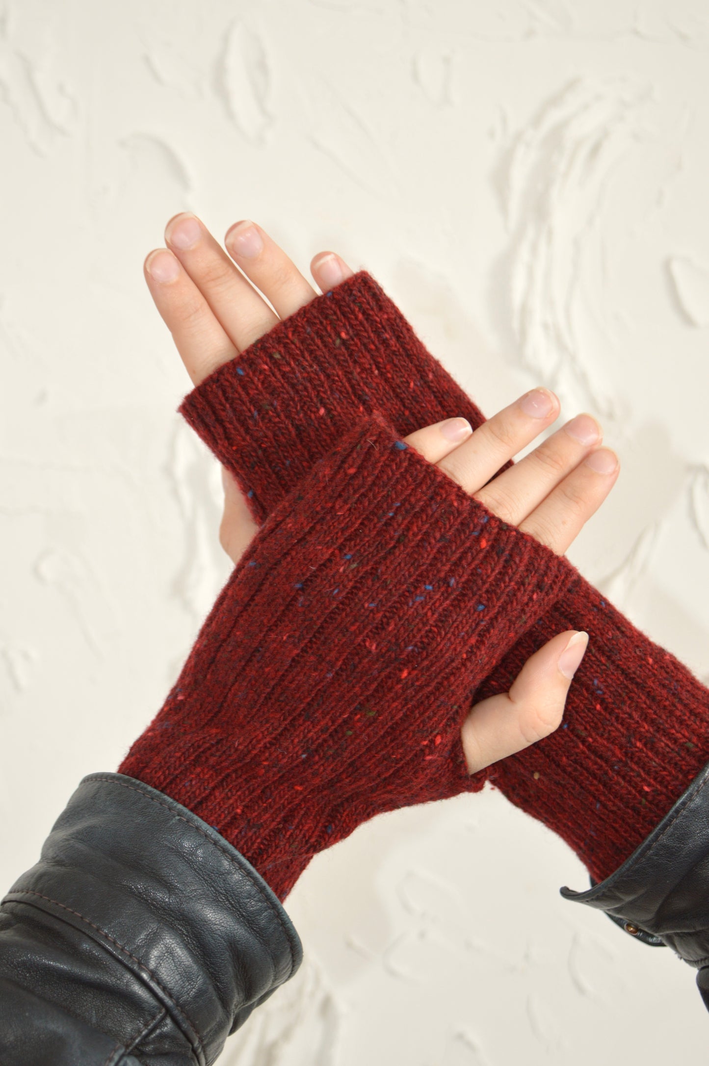 Two hands showcasing The Fingerless Gloves in red, one hand resting on top of the other.