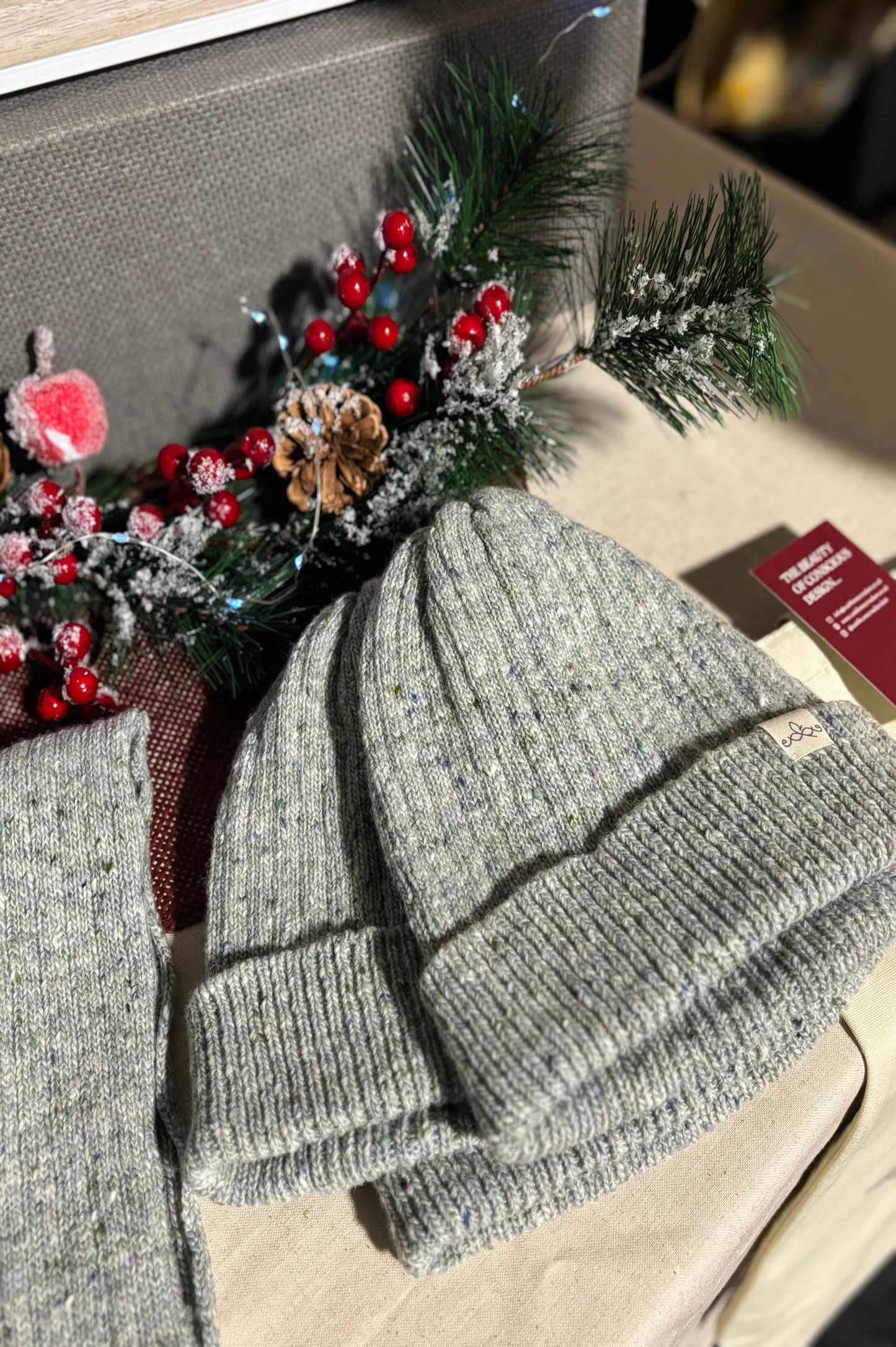 The Fitted Beanie in light grey stacked on a table with Christmas decor surrounding it