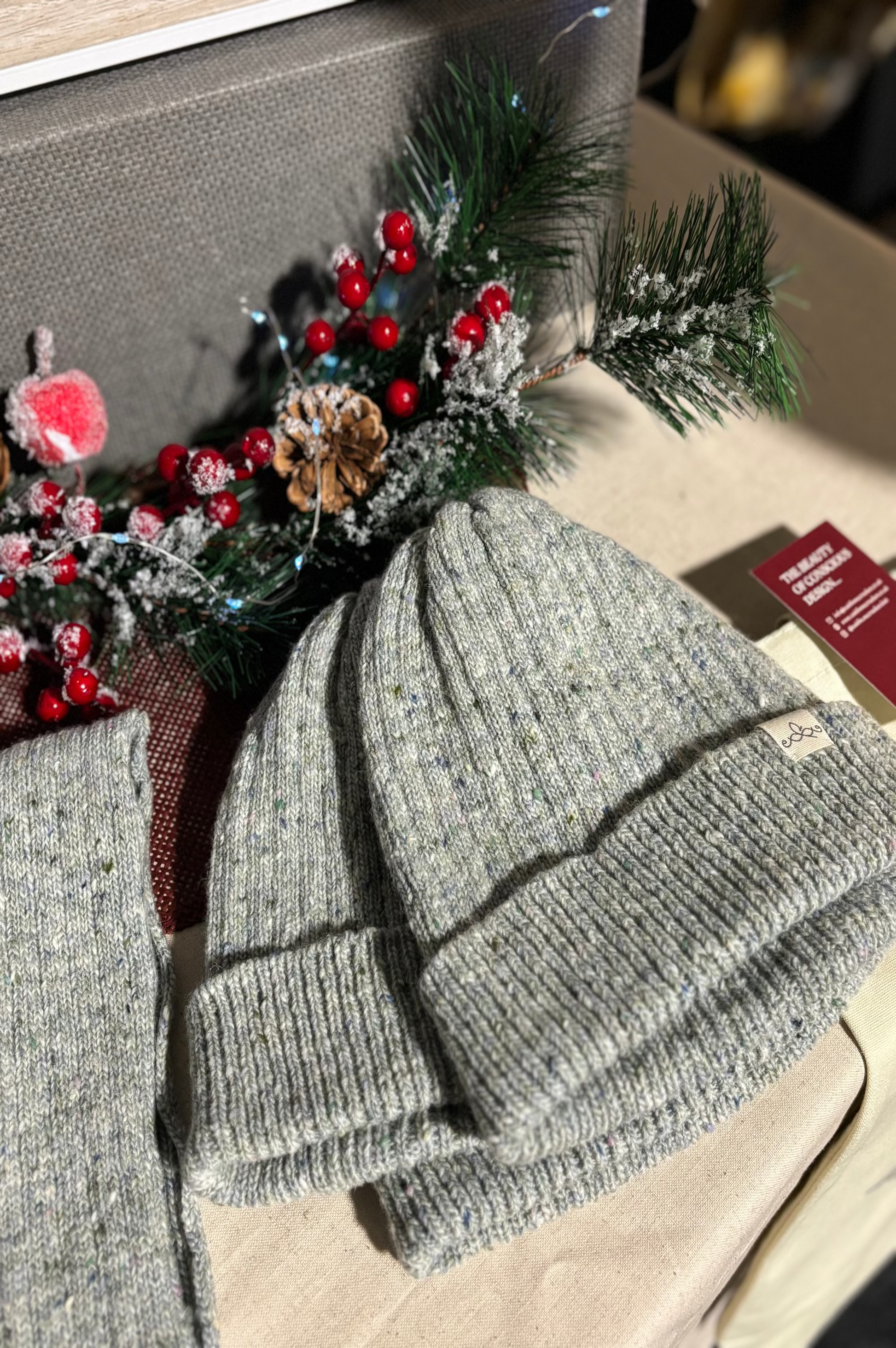 The Fitted Beanie in light grey stacked on a table with Christmas decor surrounding it